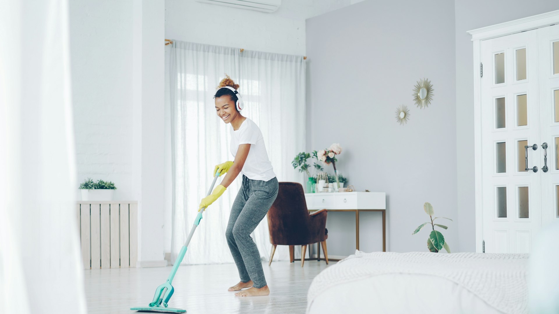 A cleaner mopping the floor of a bright, airy apartment
