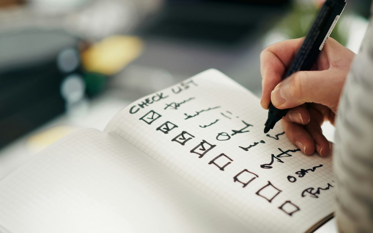 A hand ticking items off a printed checklist